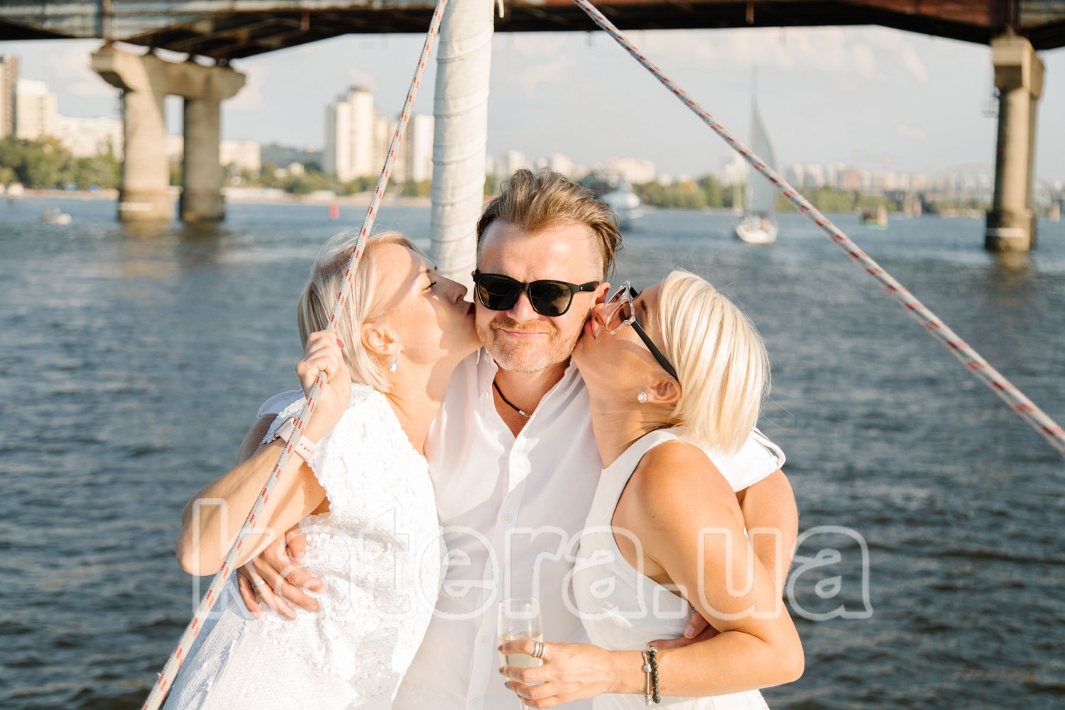 Две девушки целуют мужчину на носу яхты Пилар - katera.ua